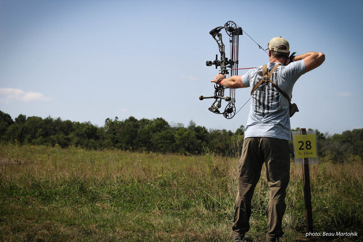 Man practicing compound bow in field. Man practicing compound bow in field.