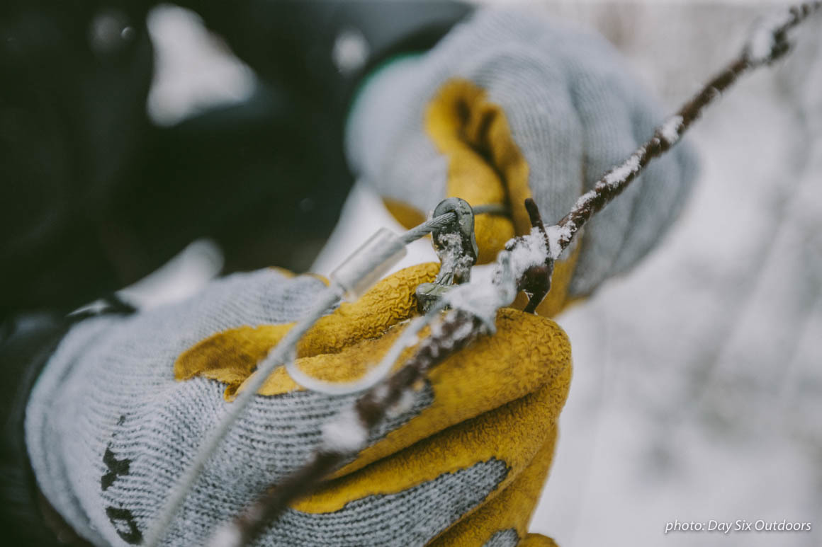 Man holding snare trap with gloves in the snow while trapping animals in the woods. Man holding snare trap with gloves in the snow while trapping animals in the woods.