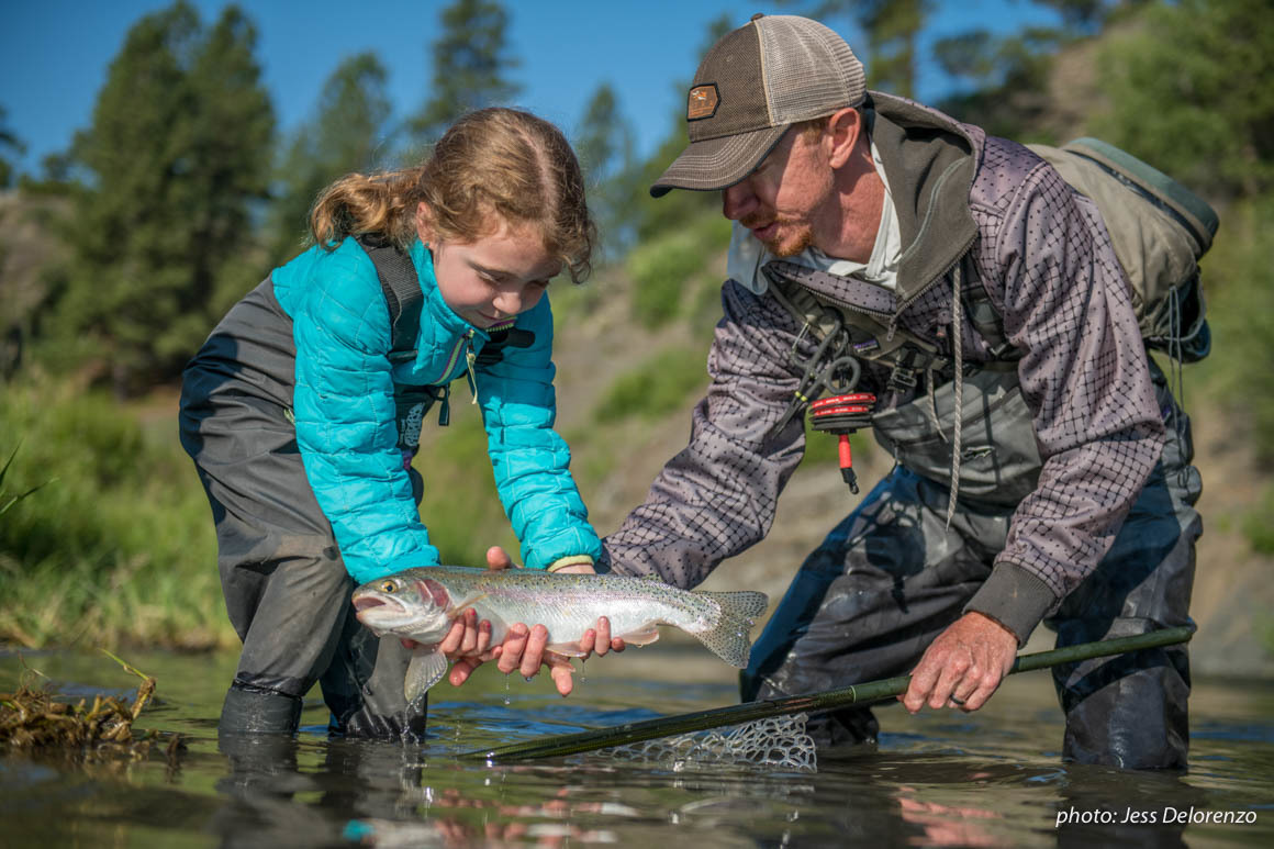 Father and daughter netting trout while fishing in a river. Father and daughter netting trout while fishing in a river.