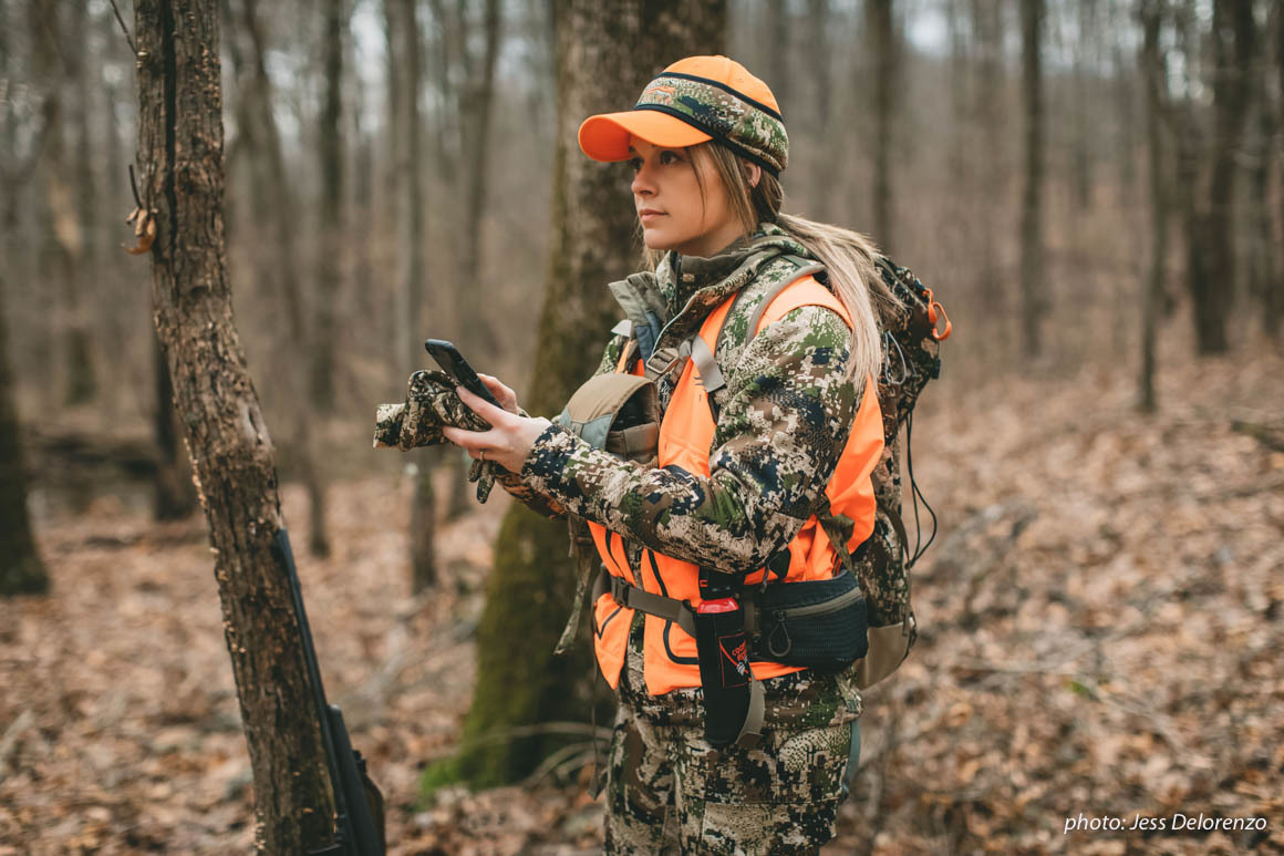 Woman hunting in woods in camouflage with cell phone. Woman hunting in woods in camouflage with cell phone.