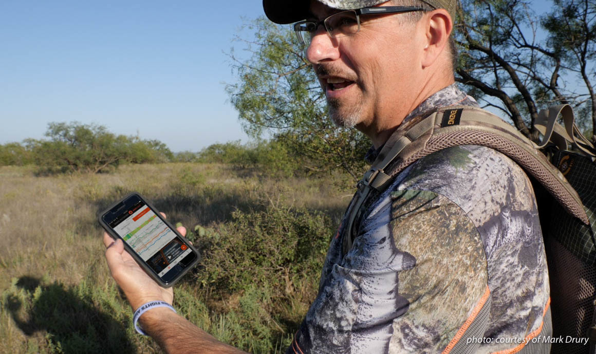 Image of Mark Drury of Drury Outdoors using the DeerCast app on his phone while hunting. Image of Mark Drury of Drury Outdoors using the DeerCast app on his phone while hunting.
