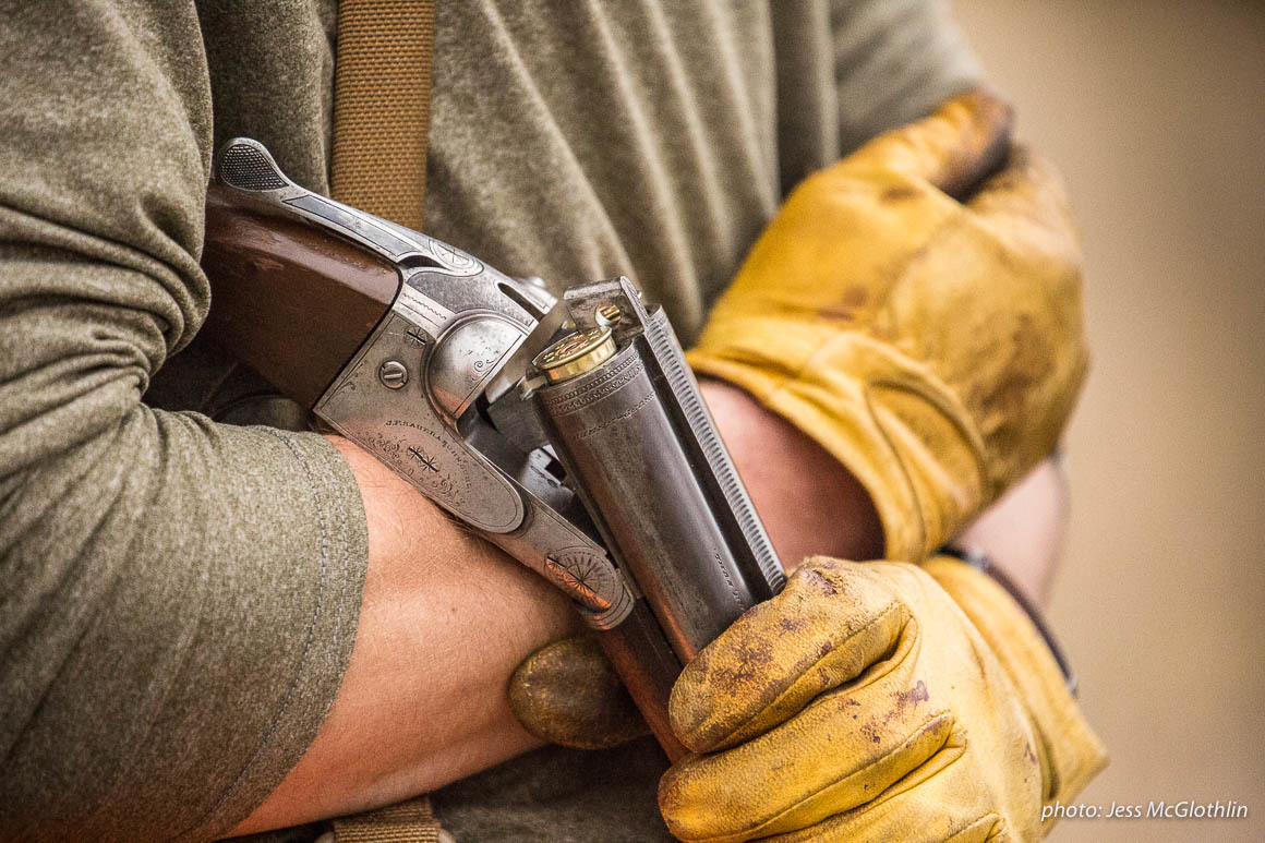 Details of a shotgun, strap vest and worn leather gloves on a hunter while upland bird hunting in eastern Montana. Details of a shotgun, strap vest and worn leather gloves on a hunter while upland bird hunting in eastern Montana.