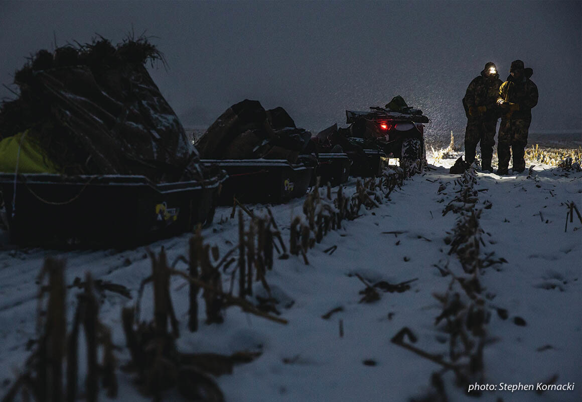 Two men looking at map with headlamp in the dark while waterfowl hunting. Two men looking at map with headlamp in the dark while waterfowl hunting.