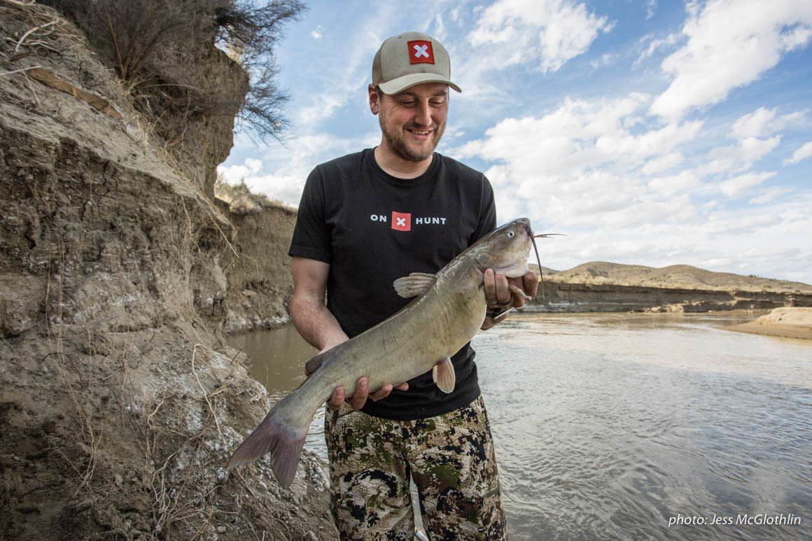 A man smiles at a catfish he caught while fishing on the Musselshell River in Montana. A man smiles at a catfish he caught while fishing on the Musselshell River in Montana.