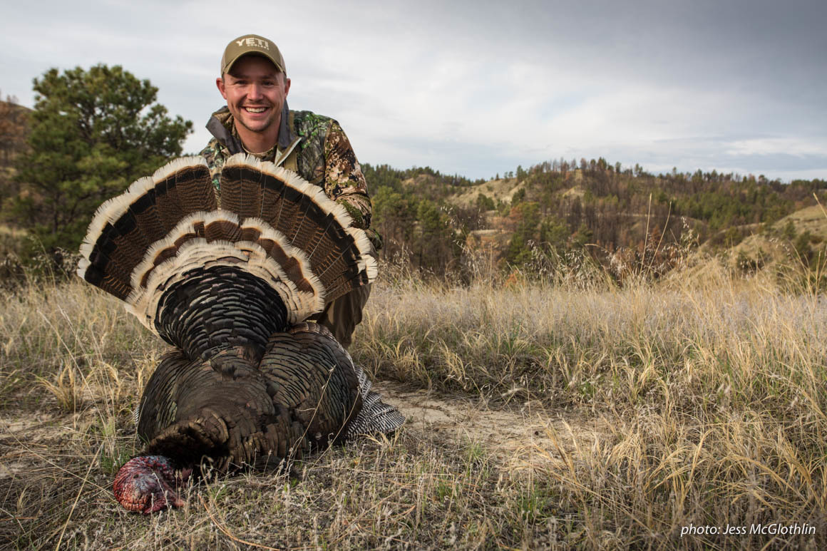 Man poses with a turkey he shot while hunting in Montana. Man poses with a turkey he shot while hunting in Montana.