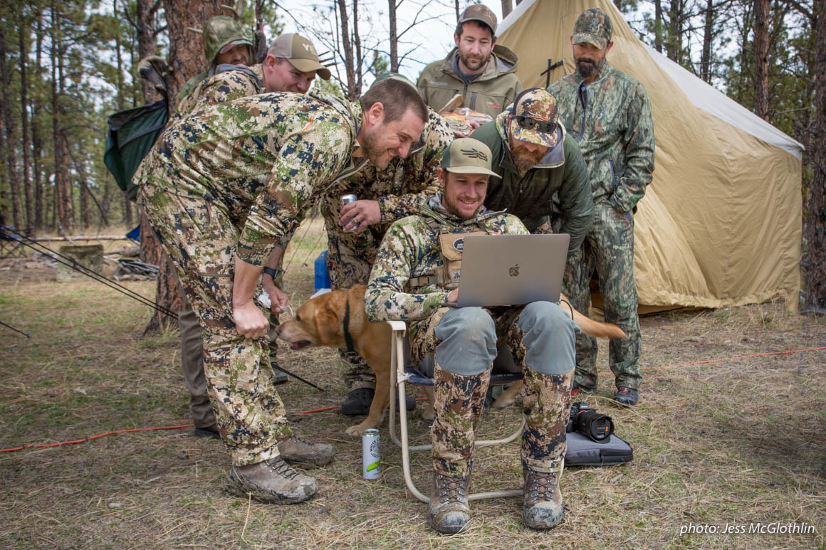 Hunters gather around a computer while in a wall tent camp in Montana. Hunters gather around a computer while in a wall tent camp in Montana.