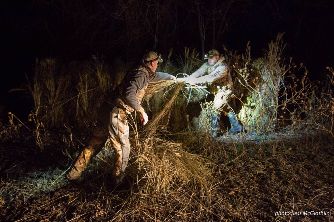 Two men work to set up a goose blind by headlamp. Two men work to set up a goose blind by headlamp.