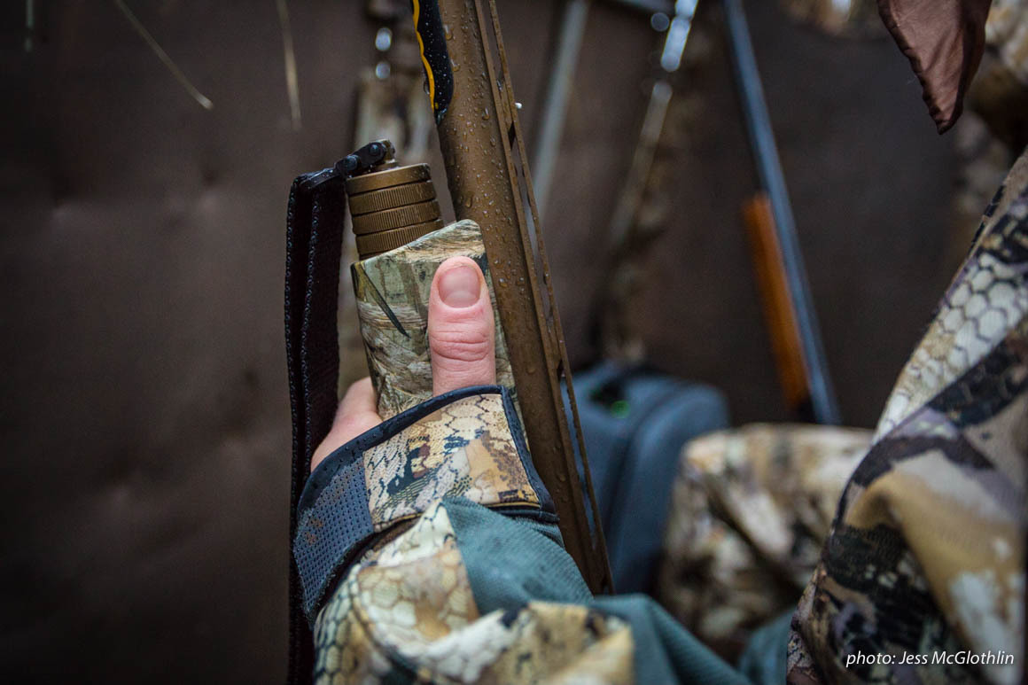 Hand of a waterfowl hunter holding a shotgun while in a goose blind. Hand of a waterfowl hunter holding a shotgun while in a goose blind.
