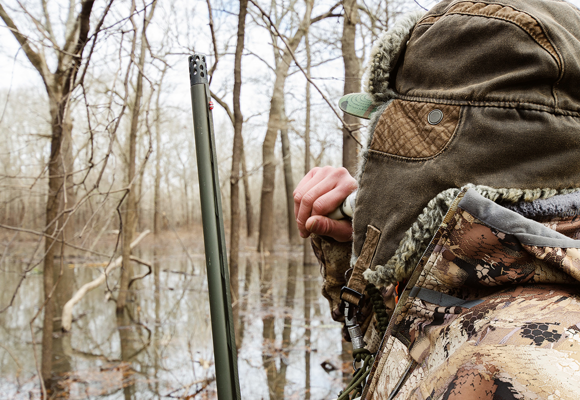 Man calling ducks from a boat in flooded timber, shotgun in hand. Man calling ducks from a boat in flooded timber, shotgun in hand.