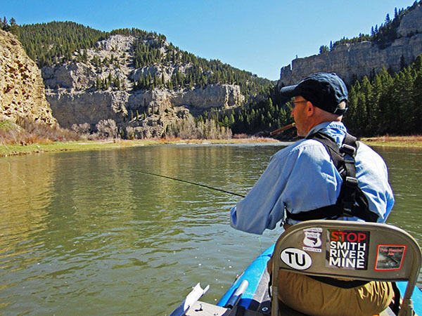 Man smoking cigar and fly fishing on the Smith River in Montana from a raft. Man smoking cigar and fly fishing on the Smith River in Montana from a raft.