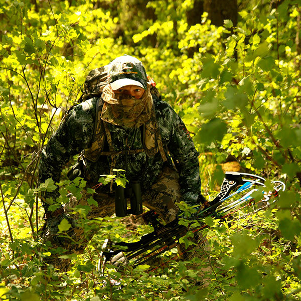 Image of hunter in full camouflage sneaking through the woods with bow in hand. Image of hunter in full camouflage sneaking through the woods with bow in hand.
