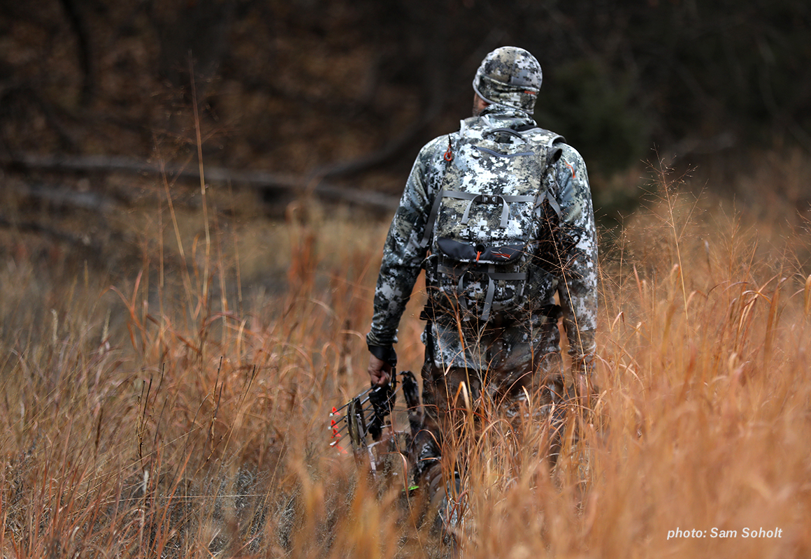 Image of a man in camouflage walking through autumn grass with a bow in hand while hunting. Image of a man in camouflage walking through autumn grass with a bow in hand while hunting.