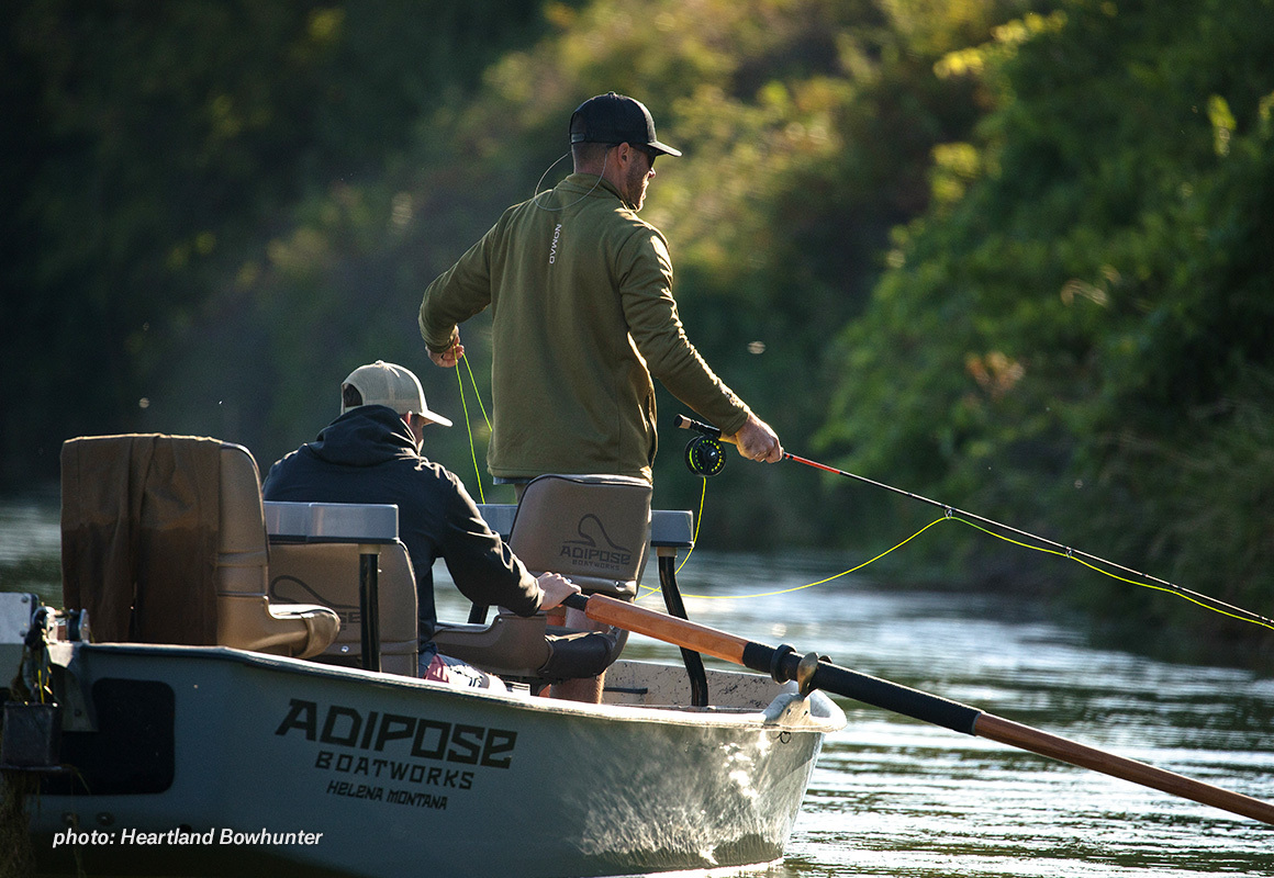 Two men fly fishing from a driftboat in the summertime. Two men fly fishing from a driftboat in the summertime.