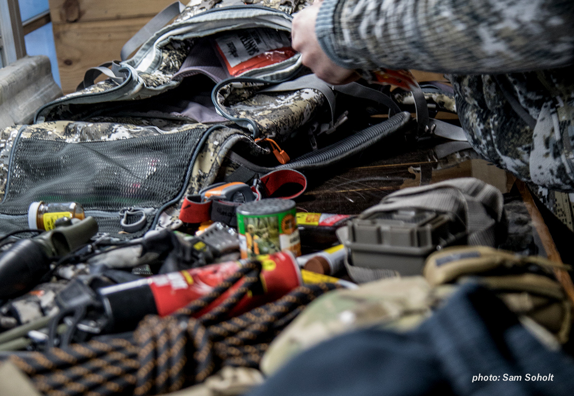 Hunter packing pack with hunting gear and medical kit in cabin. Hunter packing pack with hunting gear and medical kit in cabin.